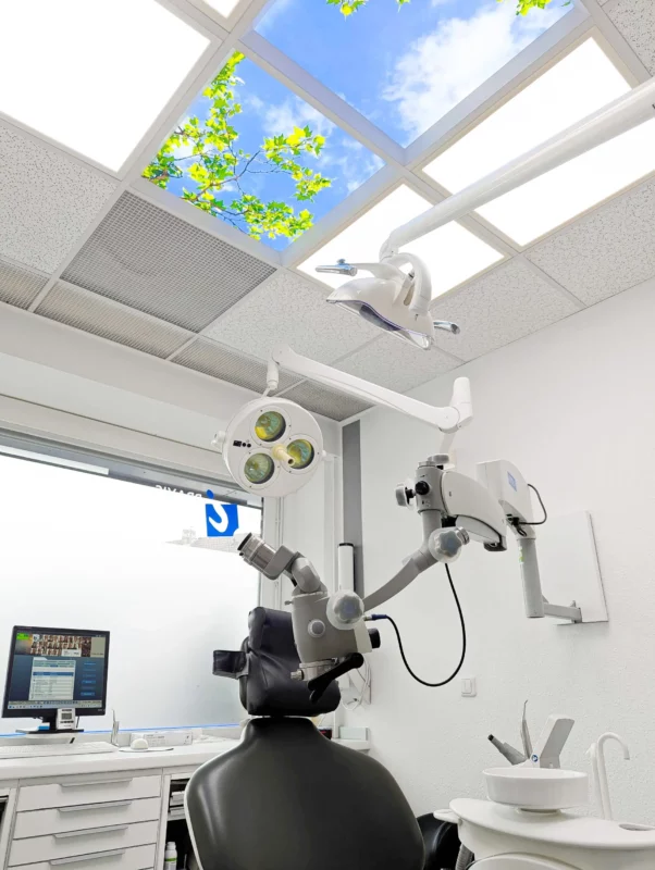 Patient-friendly treatment room with bright natural LED lighting and photo ceiling panels at Zahnarztpraxis Dr. Grünewald.